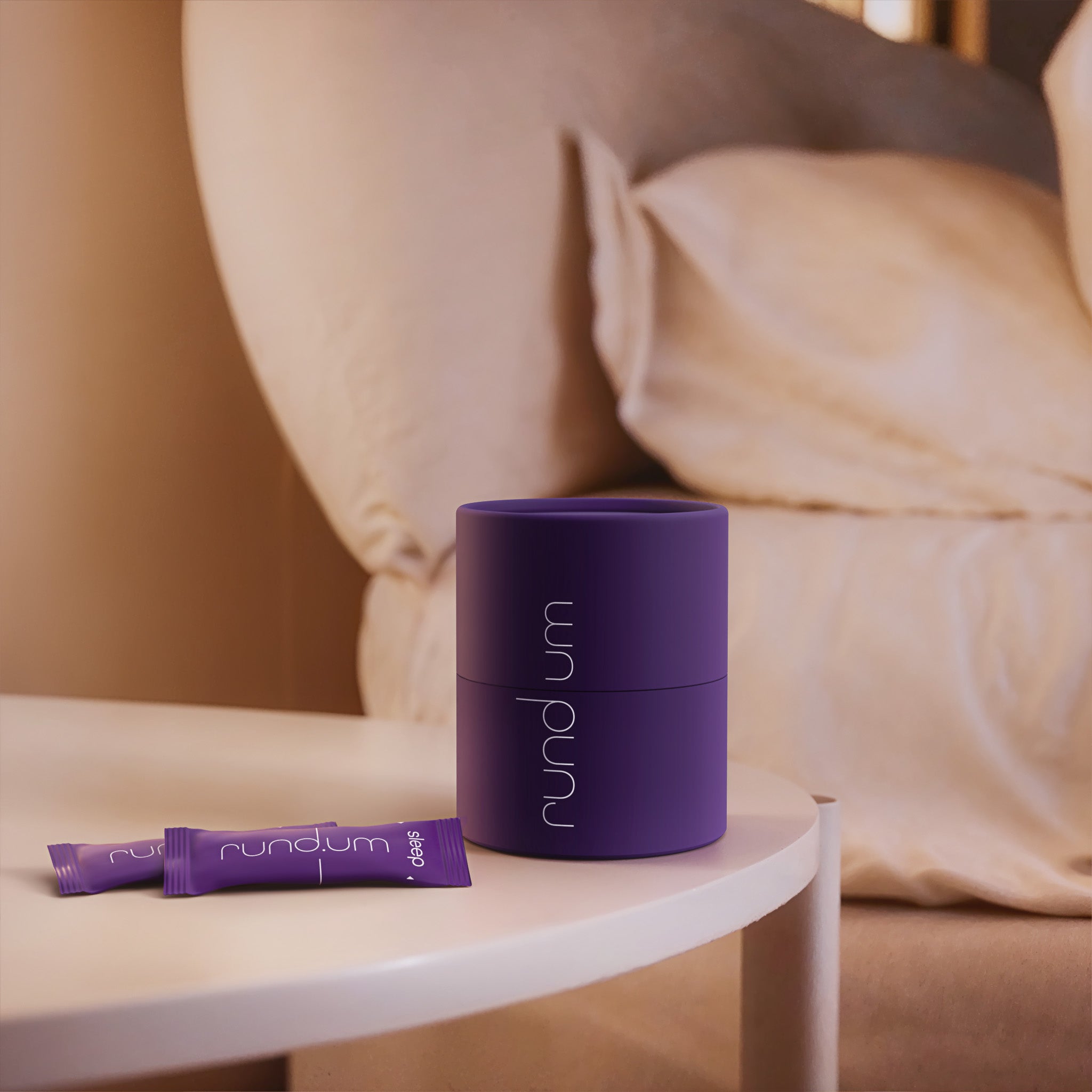 Nahrungsergänzungsmittel ‚sleep plus‘ von rundum mit lila Dose und Stick-Packungen auf einem Nachttisch