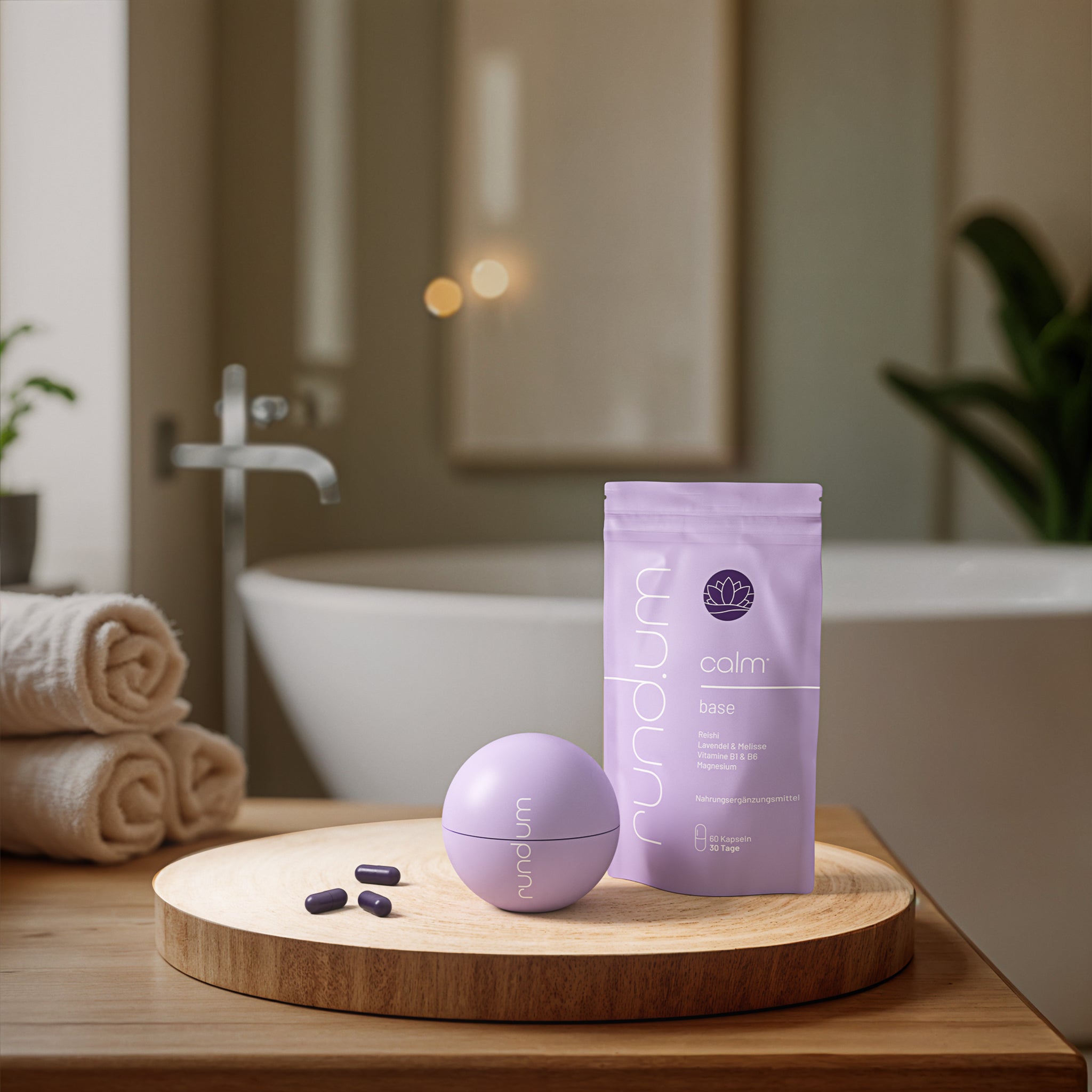 Nahrungsergänzungsmittel ‚calm base‘ von rundum in hellvioletter Verpackung, präsentiert auf Holztablett im Badezimmer