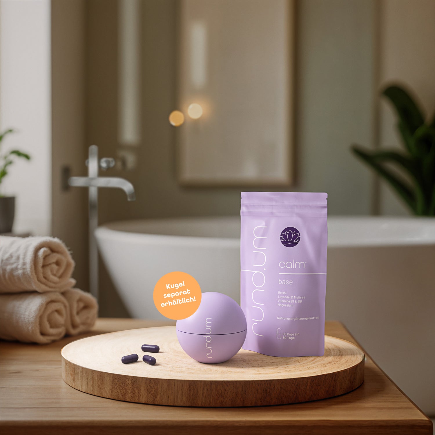 Nahrungsergänzungsmittel ‚calm base‘ von rundum in hellvioletter Verpackung, präsentiert auf Holztablett im Badezimmer mit separater Kugel