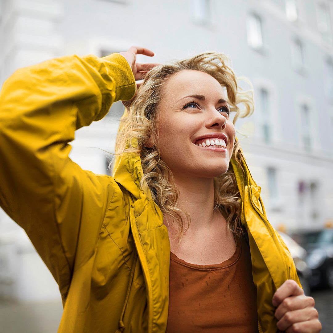 Blonde Frau im gelben Regenmantel im Regen